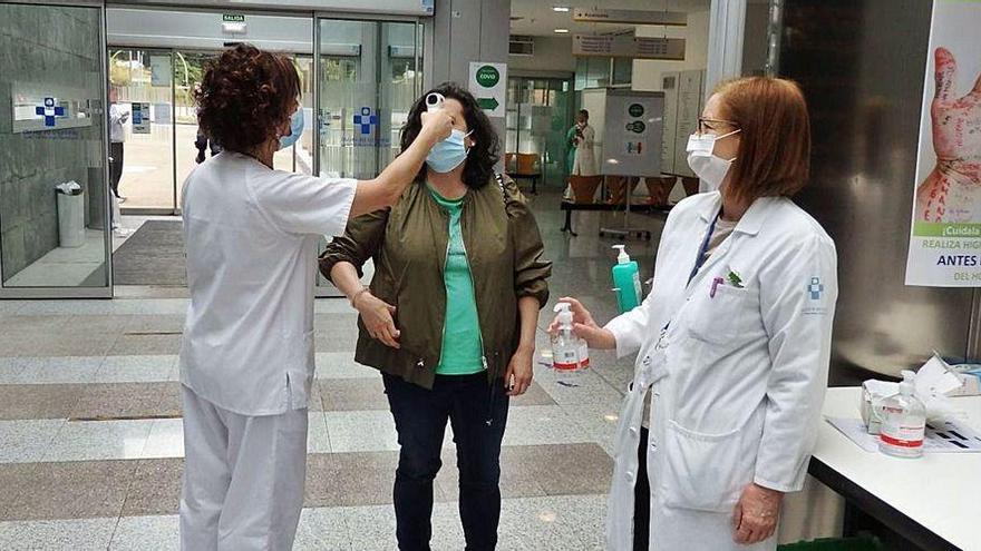 Personal sanitario, ayer, tomando en el Hospital de Mieres la temperatura a una visitante.