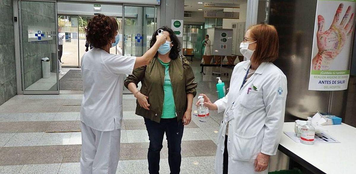 Personal sanitario, ayer, tomando en el Hospital de Mieres la temperatura a una visitante.