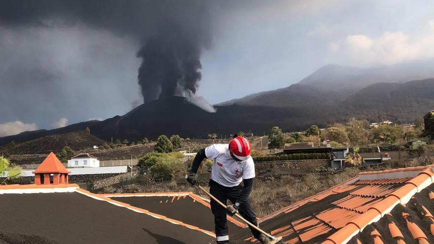 Un voluntario de Cruz Roja trabaja en la retirada de ceniza volcánica de una casa en La Palma