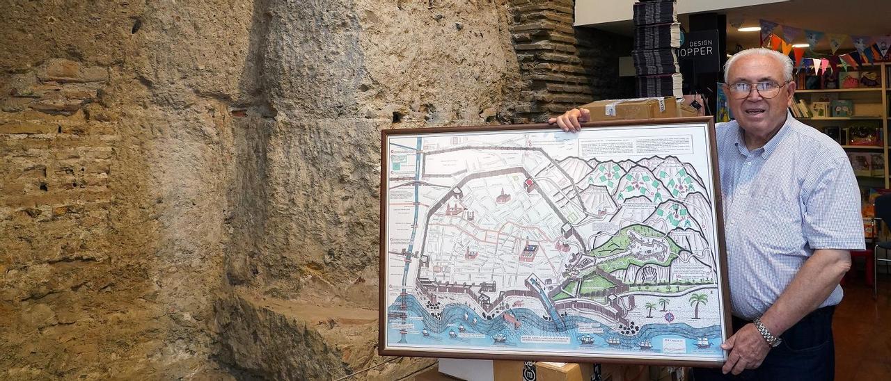 Miguel Banderas, ayer, con su plano de la Málaga musulmana, en la entrada de la librería Proteo.