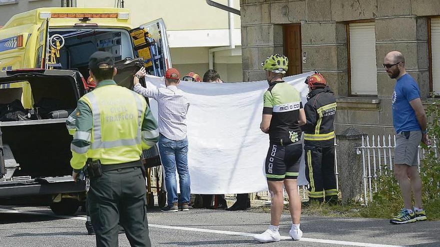 Sanitarios del 061 tapan con una sábana el cuerpo del ciclista fallecido.