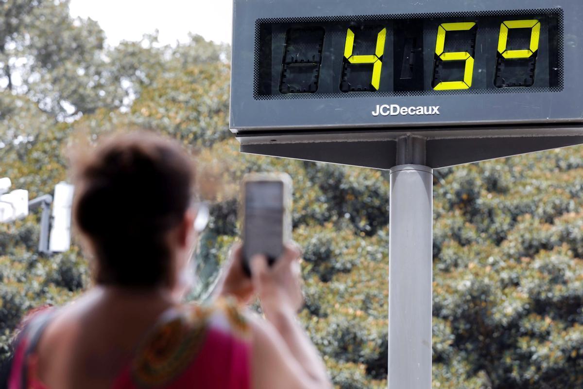 Una mujer fotografía un termómetro urbano que marca 45º.