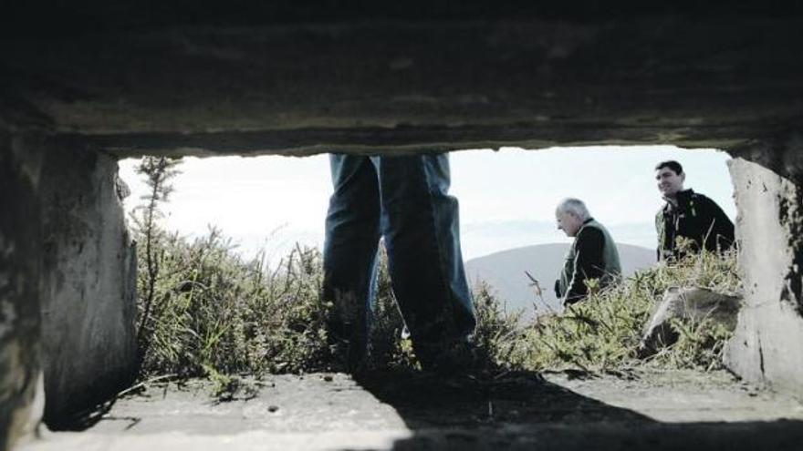 Participantes en la ruta militar por la sierra del Pedroso, en Candamo, vistos desde el interior de un nido de ametralladoras.