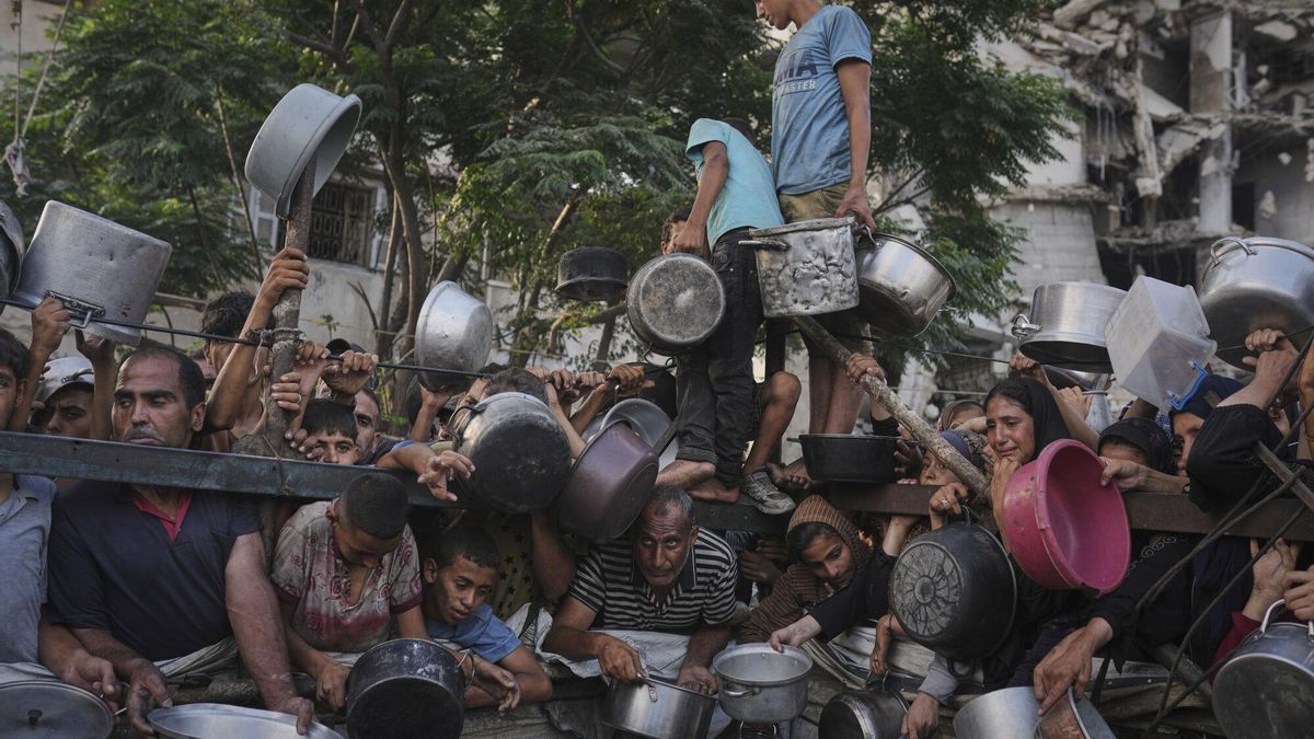 Palestinos luchan por conseguir alimentos donados en un comedor comunitario de la ciudad de Gaza.