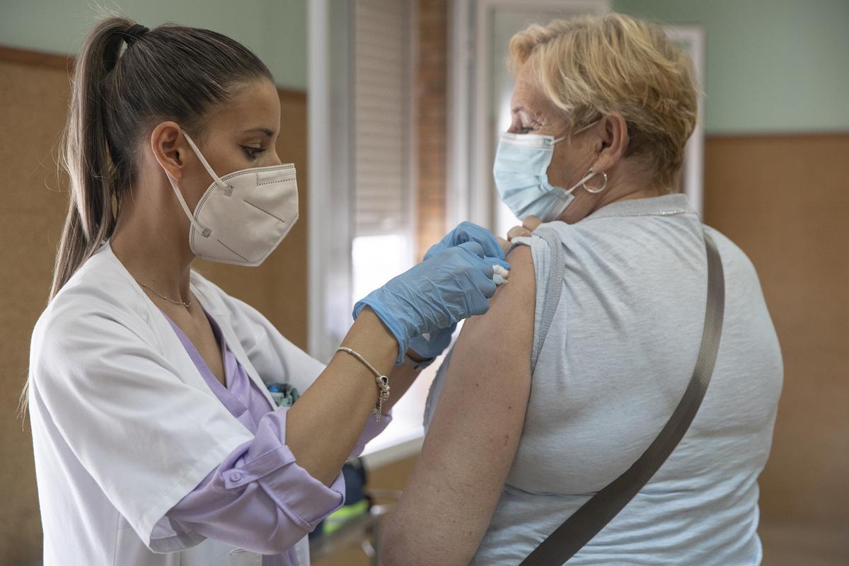 Archivo - Una enfermera vacuna a una mujer contra la gripe y el Covid. Imagen de archivo.