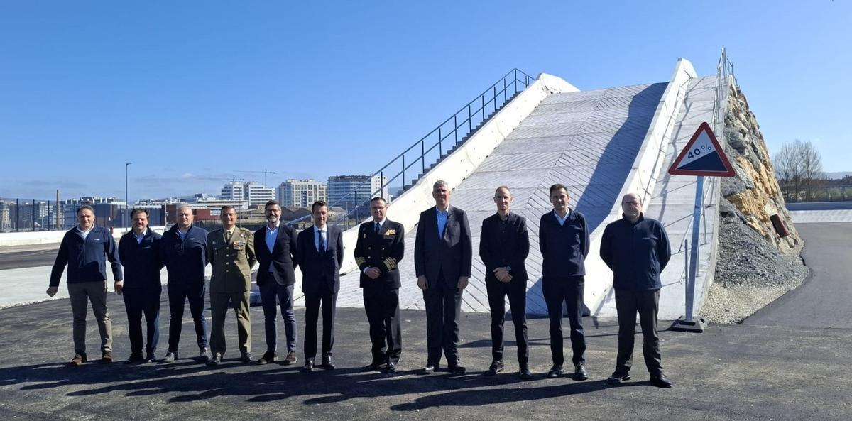 El presidente de Indra, Ángel Escribano (quinto por la izquierda), junto al director general de Armamento del Ministerio de Defensa, Aniceto Rosique, y el CEO de Indra, José Vicente de los Mozos, este lunes junto una de las rampas de la pista de blindados de la fábrica del Tallerón, en Gijón.