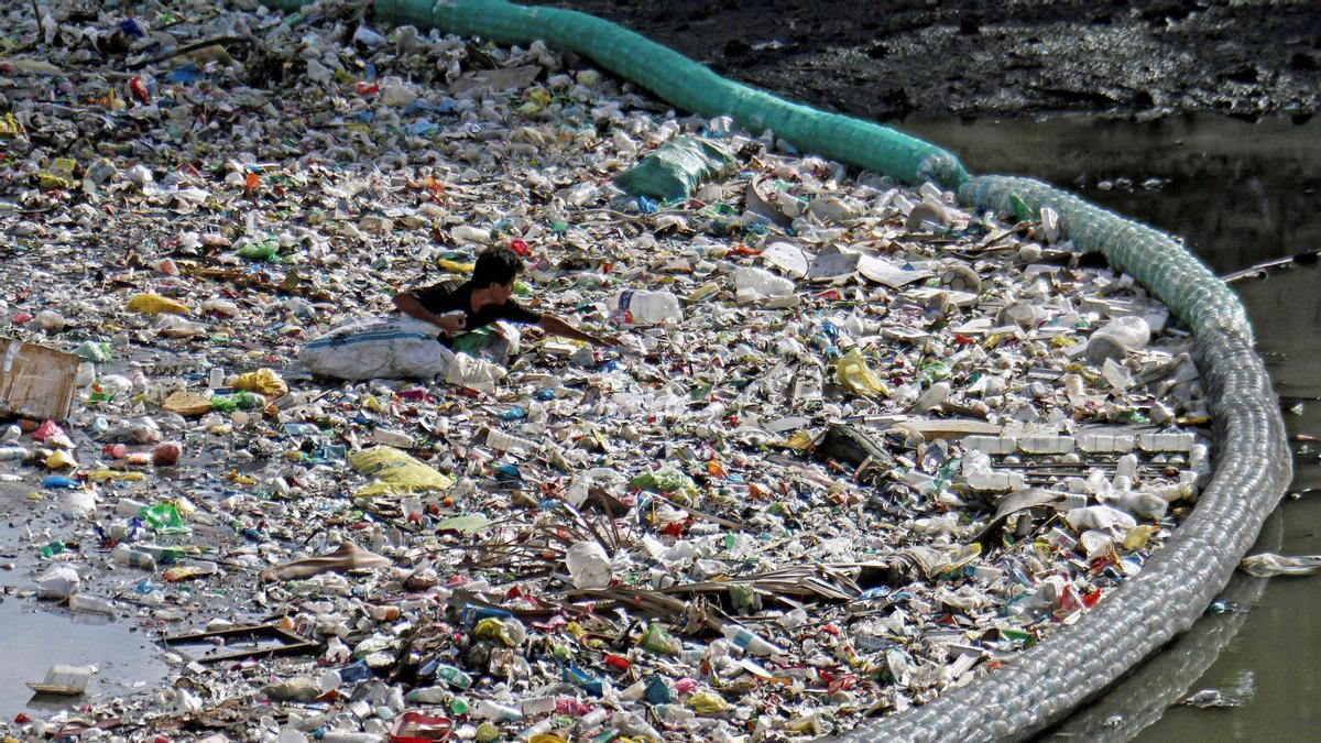 Un hombre recolecta botellas de plástico entre los residuos que una malla impide que alcancen el mar en un río en Cebu (Filipinas) el 7 de junio de 2019. Buena parte de los ecosistemas marinos están afectados por amenazas similares: la contaminación -de plástico, metales pesados, aguas fecales, residuos agrícolas, vertidos petroleros u otros-, la sobreexplotación pesquera, la destrucción de biodiversidad -por alteraciones de ecosistemas, tráfico marítimo intenso, proliferación de especies invasoras u otras causas. Madrid acoge del 2 al 13 de diciembre la Conferencia de las Partes (COP25) de la Convención Marco de Naciones Unidas (CMNUCC), una cita que reunirá a representantes de 195 países y en la que la se hablará de nuevas estrategias para la lucha contra la crisis climática. EFE/Archivo/ADOLFO ESPINOSA