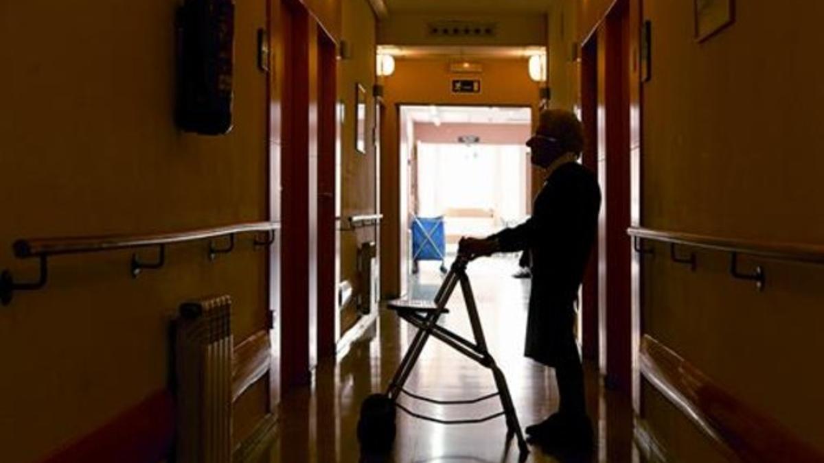 Una anciana camina con ayuda de un andador  en una residencia geriátrica de Barcelona.