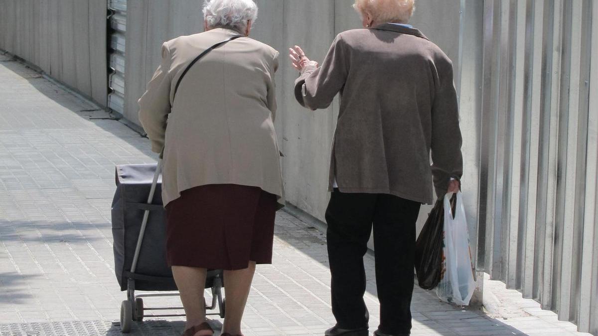 Dos personas mayores caminan por la calle.
