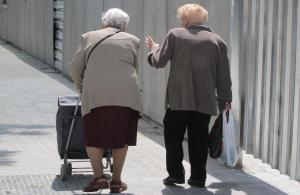 Dos personas mayores caminan por la calle.