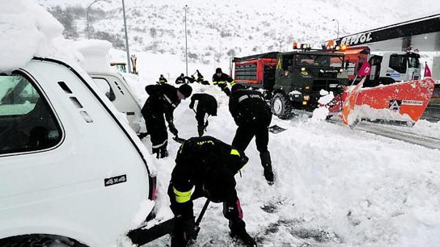 en acción. La intensa nevada del pasado domingo en la autopista del Huerna dejó escenas insólitas, como la de los equipos de militares trabajando a  destajo para descubrir de nieve los coches atrapados en la vertiente leonesa, en la imagen superior junto a una quitanieves del Ejército.