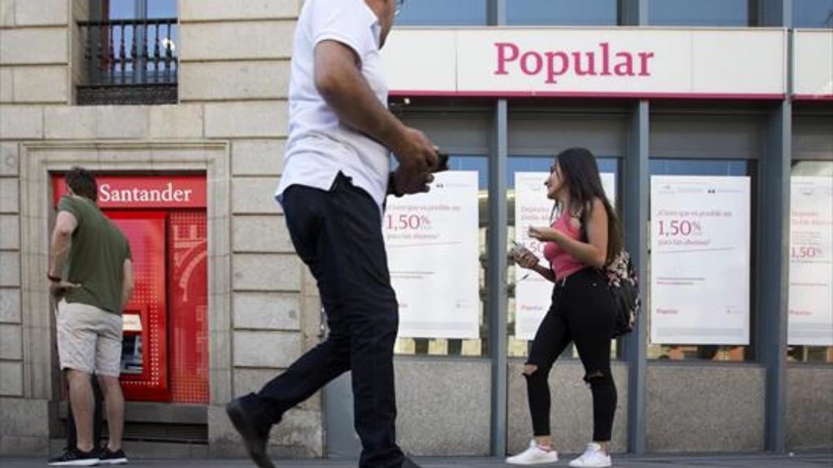 Un cajero automático del Santander junto a una sucursal del Popular en Madrid, ayer.