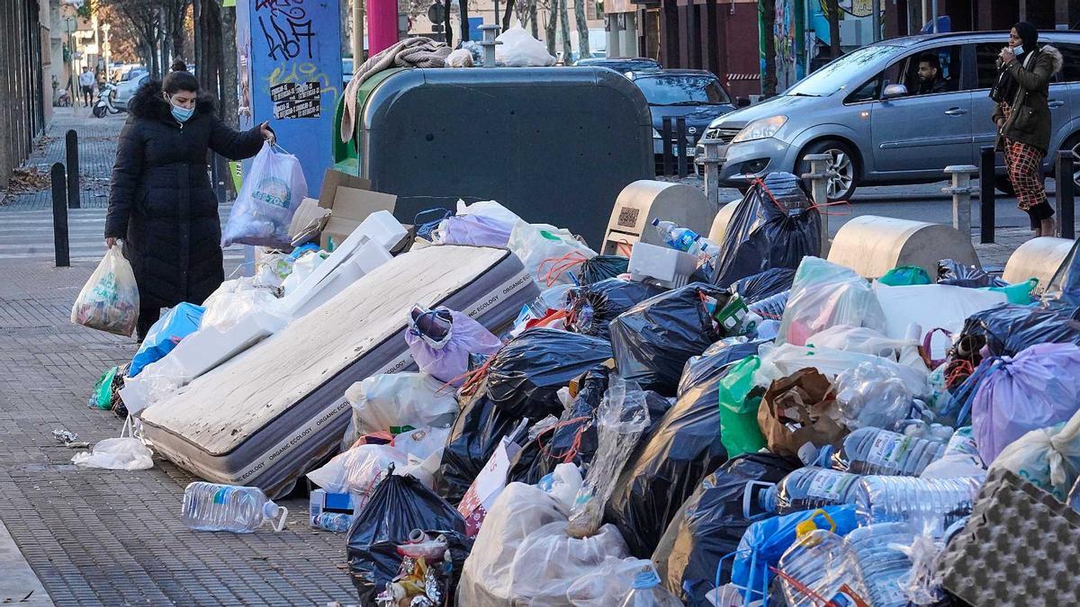 Una ciutadana llança la brossa fen una illa de contenidors a Salt