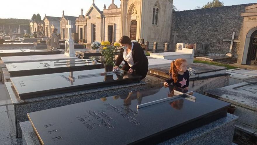 Asenet García, junto a su hija Marta, limpiando las lápidas de la familia en Camplengu, Llanes. | Eva San Román