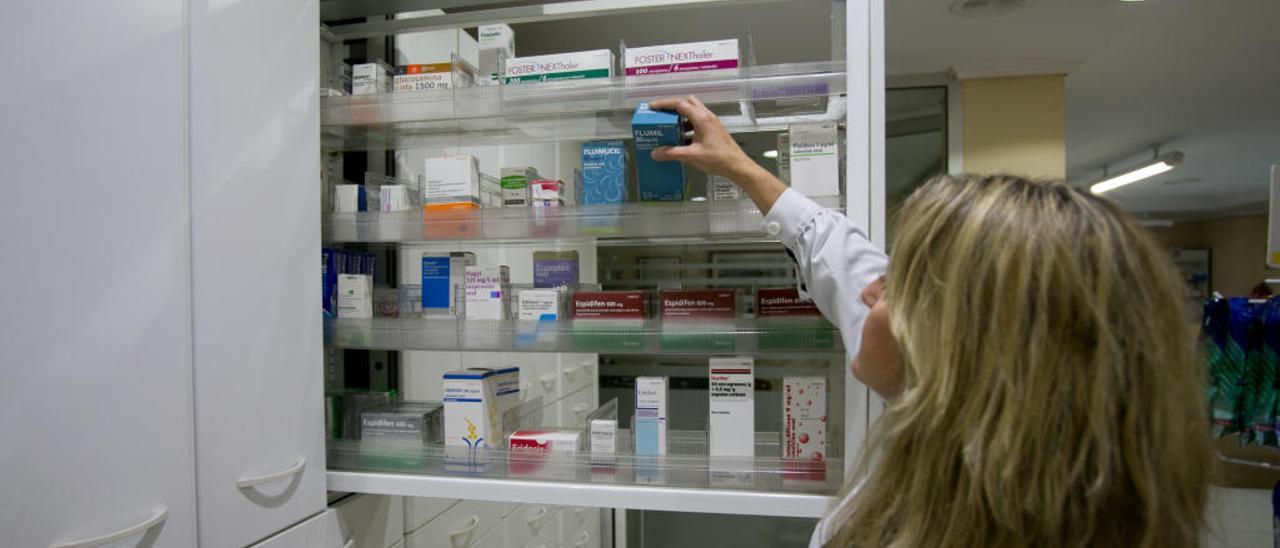 Una farmacéutica busca un medicamento en el almacén de una botica.
