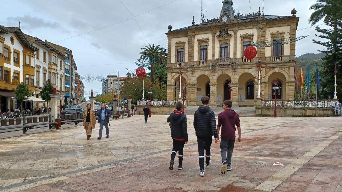 A la derecha de la imagen, tres jóvenes, cruzando la plaza del Ayuntamiento de Villaviciosa junto a otros vecinos, en una imagen tomada el pasado diciembre.