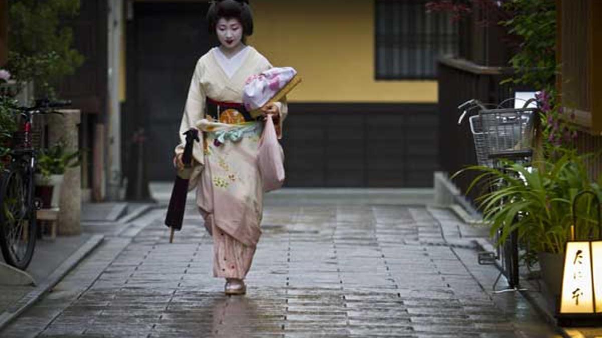 Una geisha camina en el distrito de Gion en Kioto al encuentro de un cliente.
