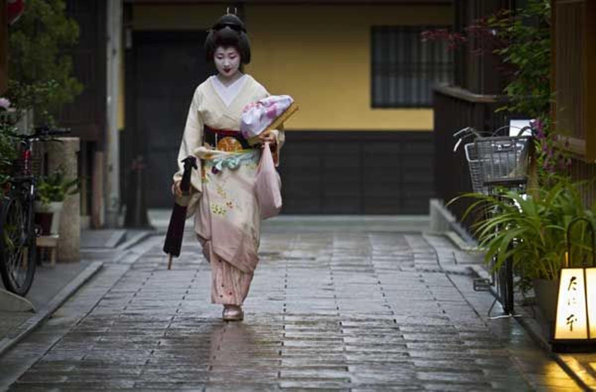 Una geisha camina en el distrito de Gion en Kioto al encuentro de un cliente.