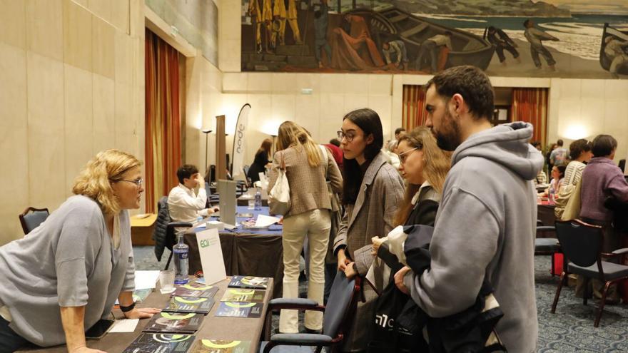 Tres estudiantes reciben información en uno de los puestos de la feria de estudios.