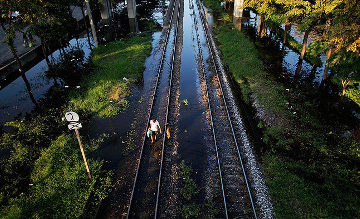 Un home i el seu gos caminen en un carril de tren inundat a Bangkok, Tailàndia.