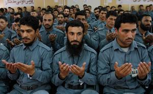Oficials acabats de graduar de la policia afganesa resen durant la seva graduació a Kabul, l’Afganistan.
