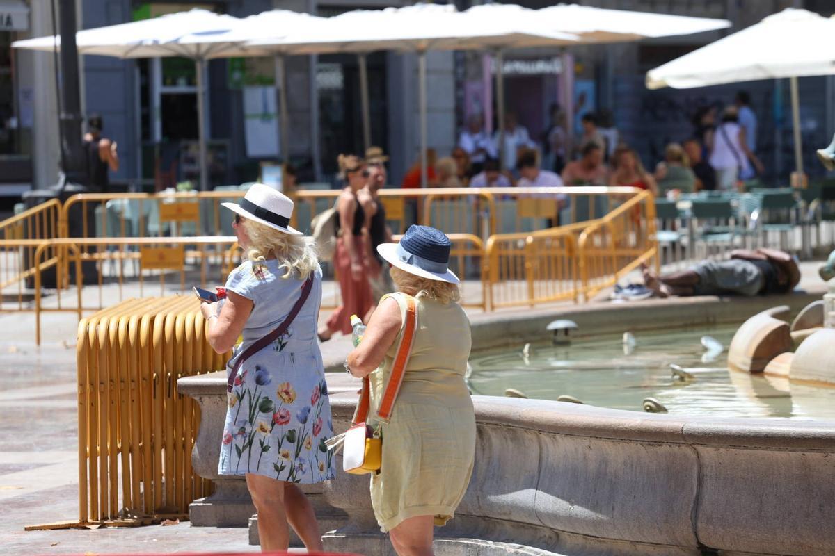 Dos turistas en la plaza de la Virgen.