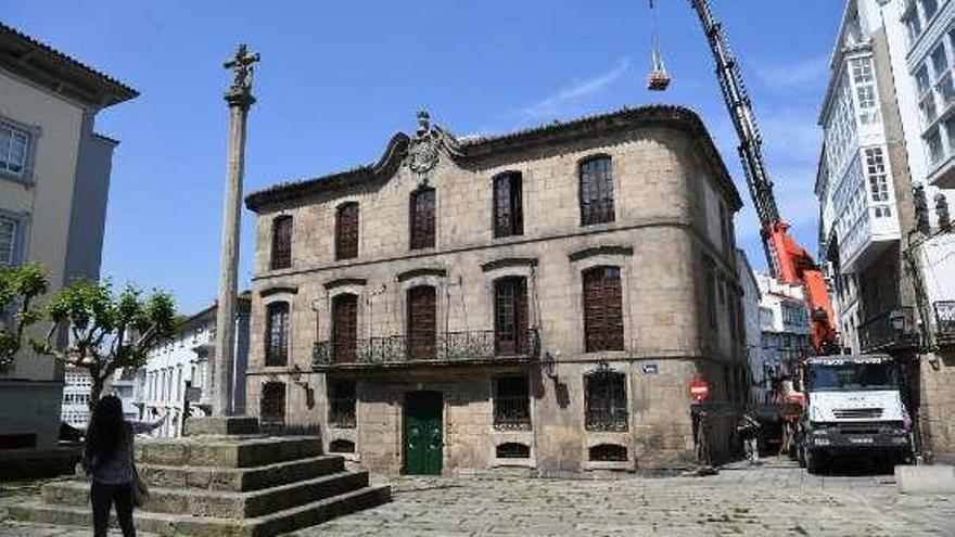 Una grúa deposita material de obra en la cubierta de la Casa Cornide