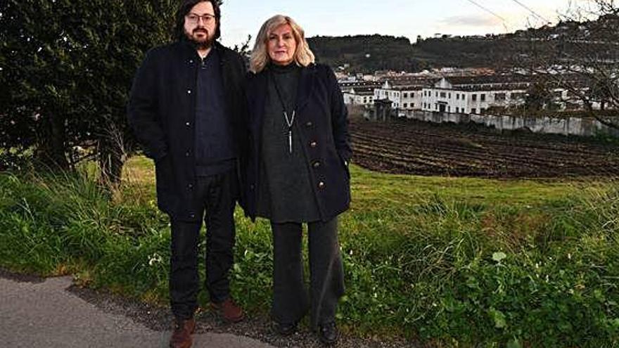 Álvaro Pérez y Belén Prego, ambos de la asociación Campo de Pena de Palavea, con la fábrica de armas detrás.