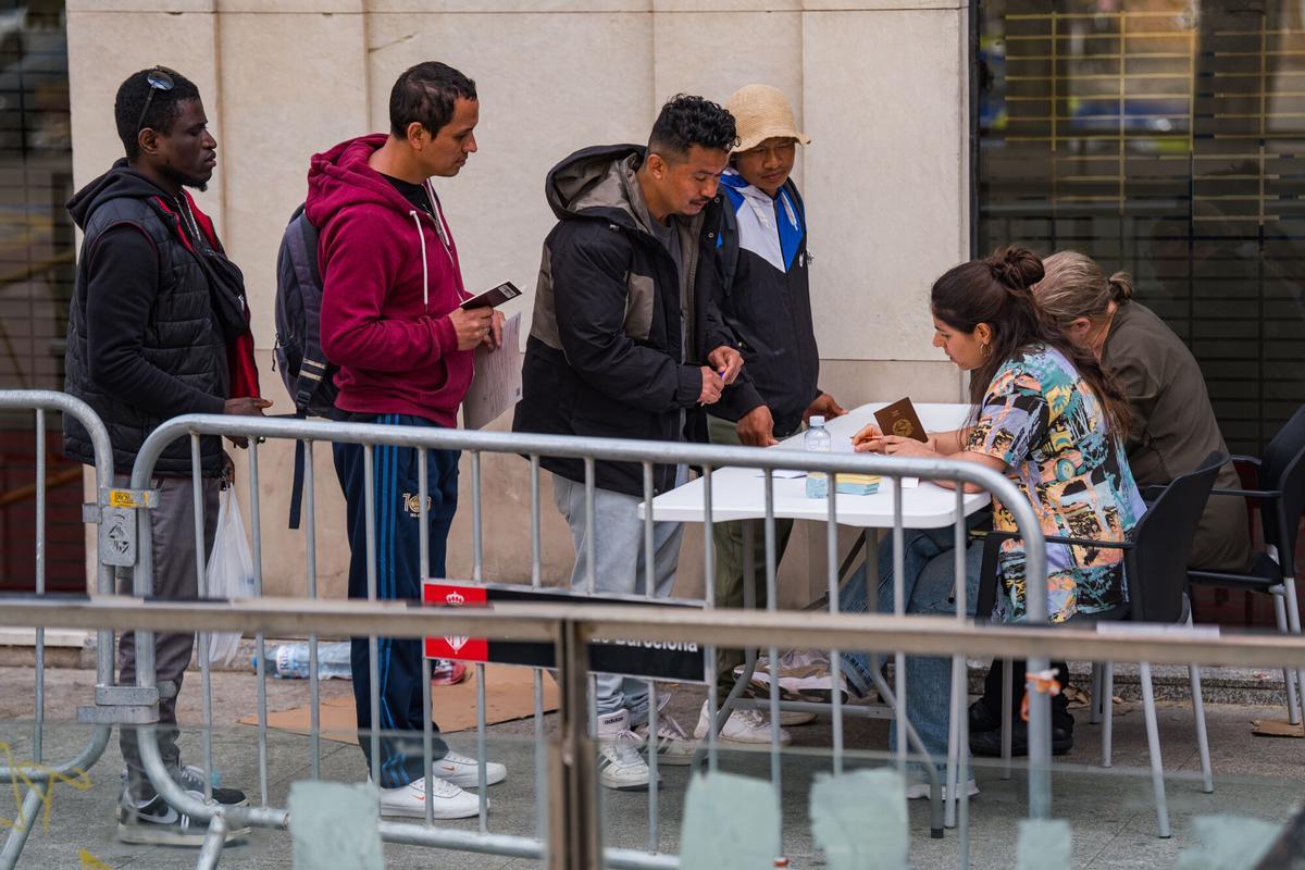 Caos y una larga cola de personas que esperan regularizar su situación en España en la Oficina de Benestar Social i Família de Barcelona-Sants/Eixample.