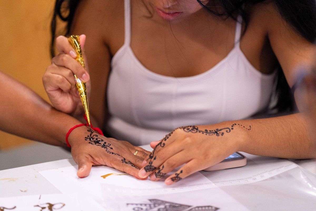 Un grupo de mujeres de entre 20 y 80 años, vecinas del barrio de la Trinitat Vella y usuarias del Centre de Vida Comunitària, participan en un taller de henna dentro de un casal de verano femenino.
