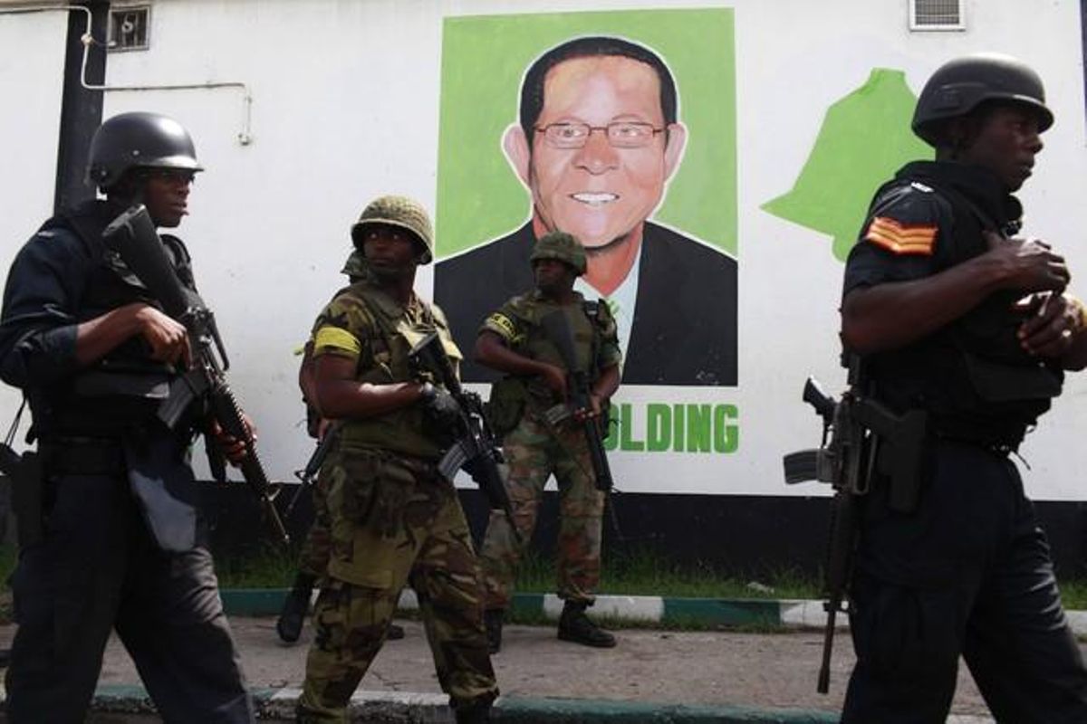 Policies i militars davant d’un mural a la imatge del primer ministre, Bruce Golding, que lidera una guerra implacable contra el tràfic de drogues. El 2009, les forces armades van matar 224 ciutadans.