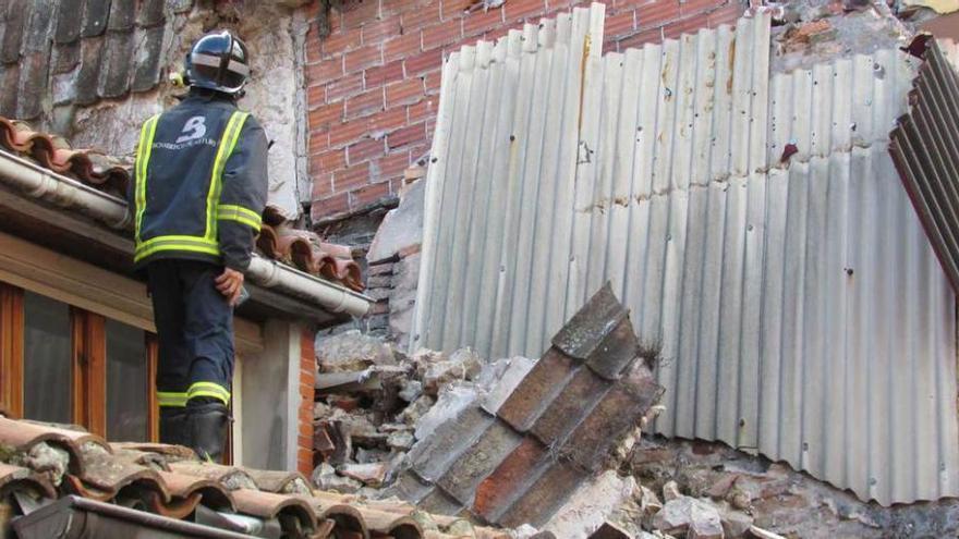 Un bombero inspecciona, ayer, el material desprendido sobre el edificio número 13 de la calle Manuel Cue de Llanes.