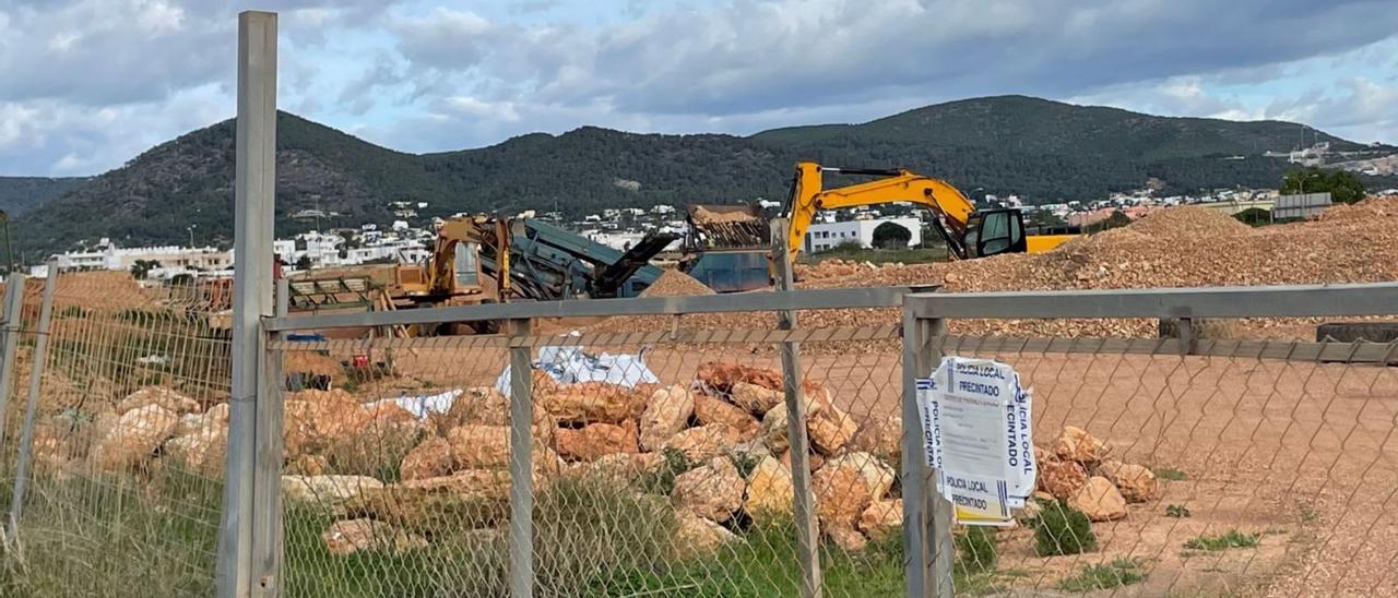 La orden de paralización precintada en la verja de entrada a la finca y, al fondo, las máquinas paradas. | D. I.