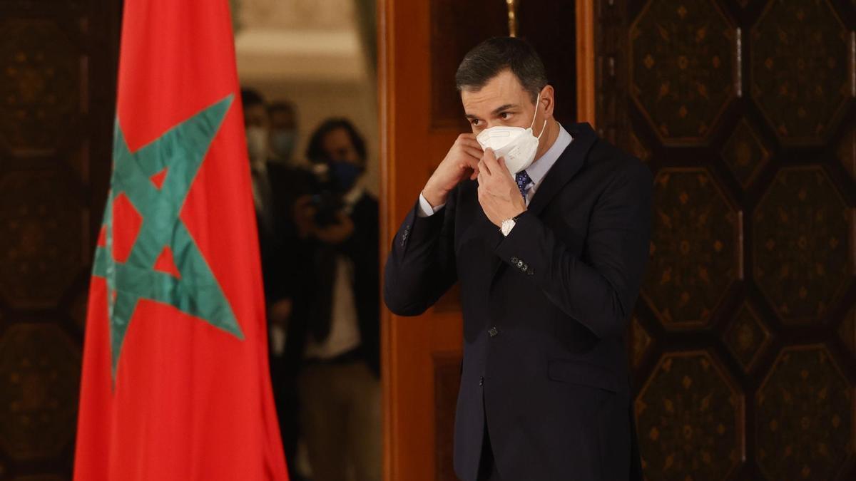 Pedro Sanchez junto a una bandera de Marruecos.