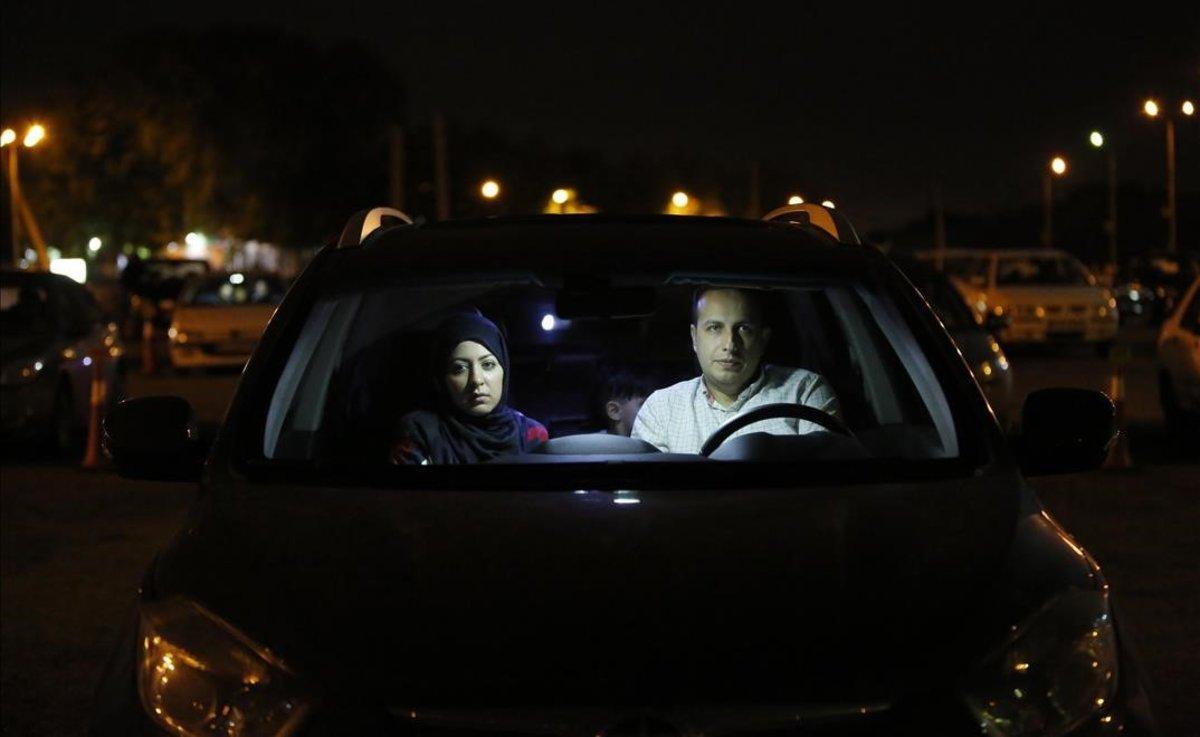 Una familia iraní, dentro de su coche, participa en una ceremonia religiosa en Teherán.