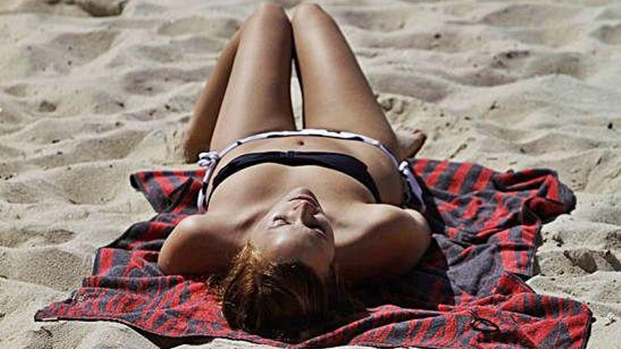 Una mujer toma el sol en una playa.