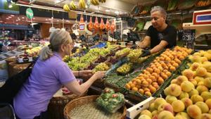 Una mujer, en un puesto de frutas y verduras en un mercado de Barcelona.