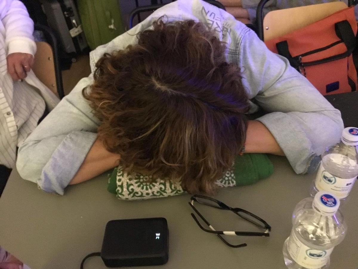 Una de las afectadas descansa, lo que puede, con la cabeza apoyada en una de las mesas de la sala donde les llevaron hasta la llegada del bus.