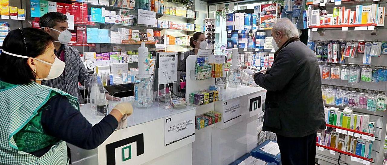Dos personas mayores de 64 años piden sus mascarillas en una farmacia.