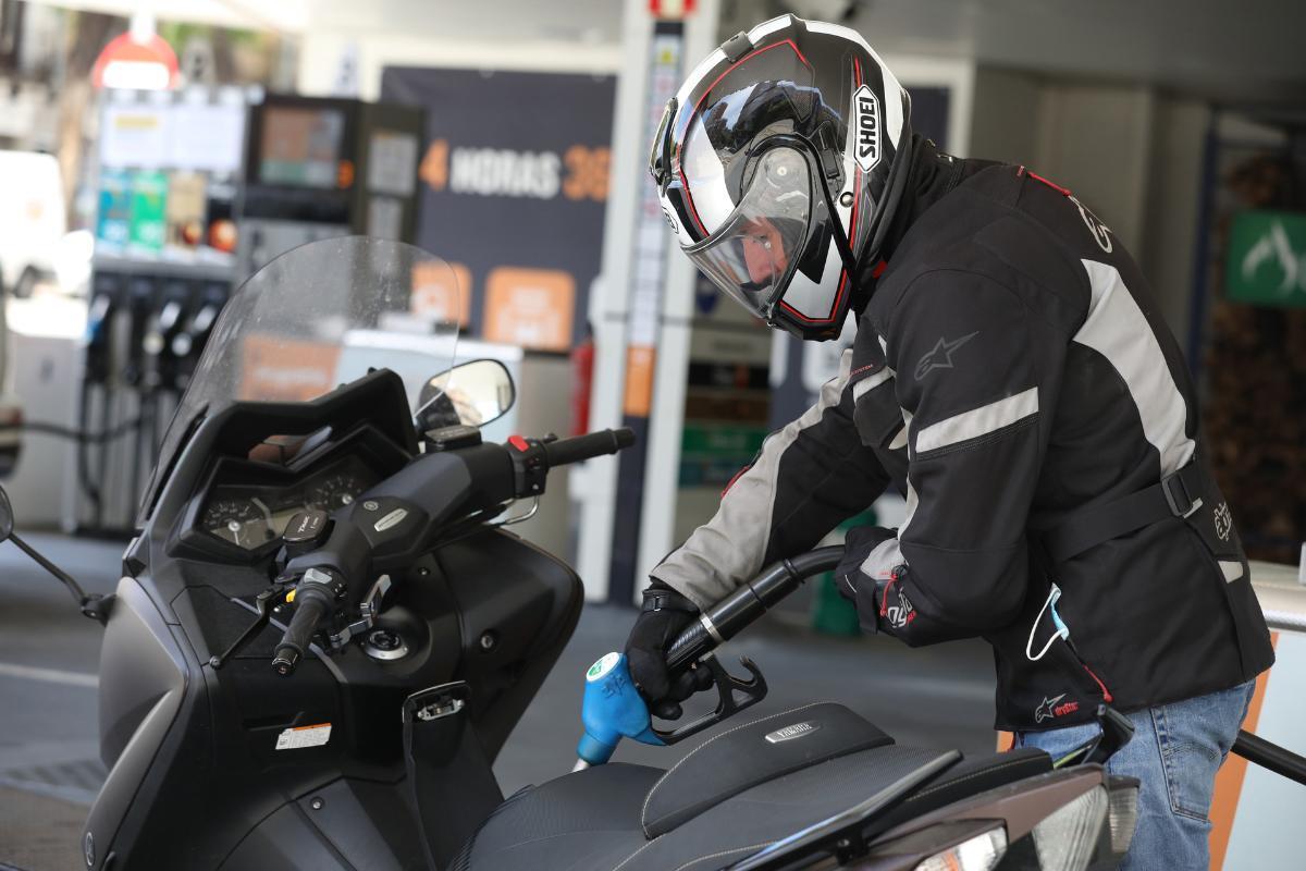 Un hombre echa gasolina a su moto.