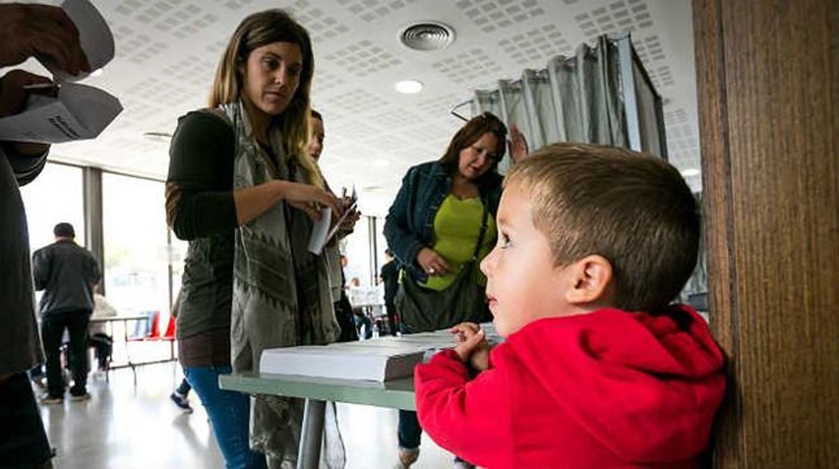 Zarek observa els seus pares en el moment de votar al col·legi electoral de Mira-sol, a Sant Cugat.