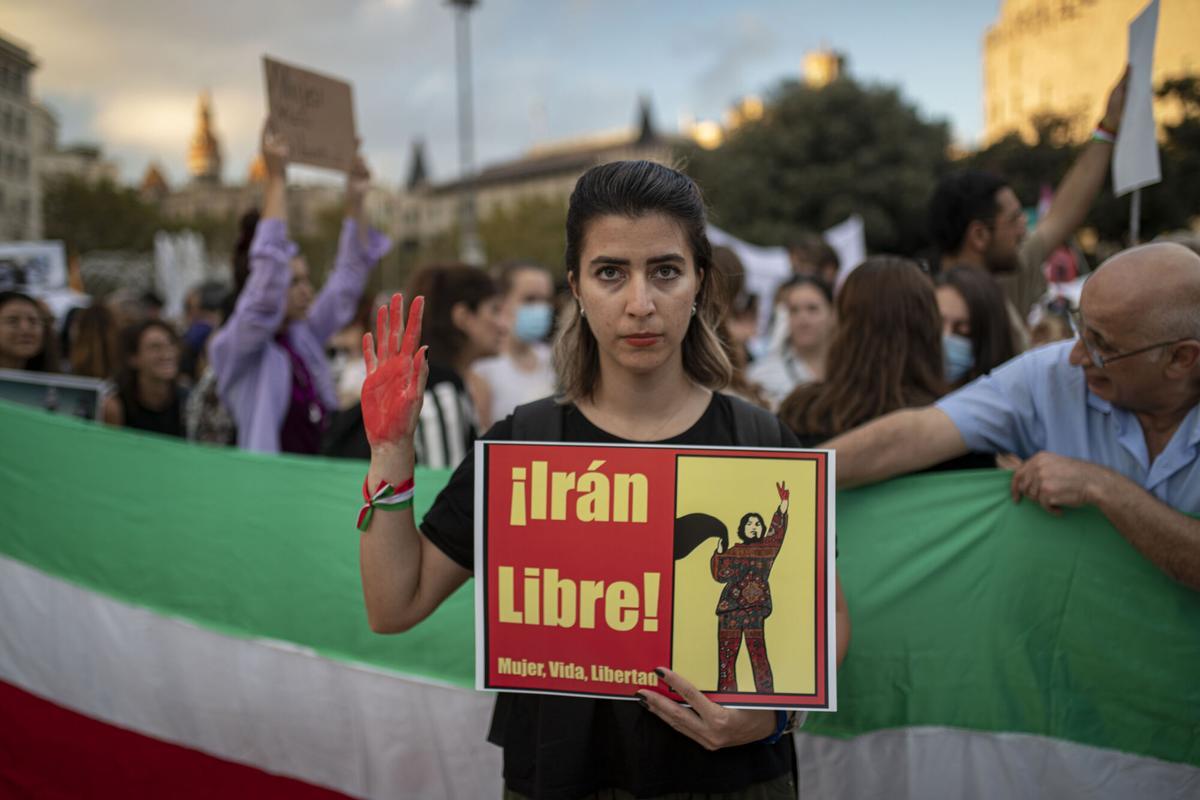 Una joven sujeta un cartel en el que pone 'Irán Libre' durante la manifestación en Barcelona contra el régimen Iraní tras la muerte de Mahsa Amini, a 15 de octubre de 2022, en Barcelona (España). Unas 300 personas se han concentrado en Barcelona para defender los derechos de las mujeres en Irán tras la muerte de Mahsa Amini, que murió bajo custodia tras ser detenida por la 'policía de la moral' al llevar mal puesto el vuelo.