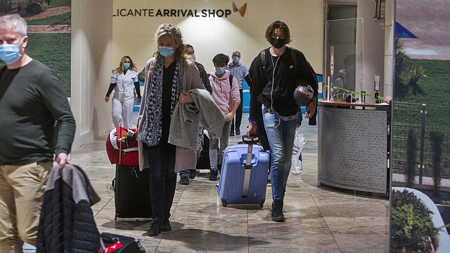 Un grupo de pasajeros británicos accediendo a la planta de llegadas del aeropuerto. Sobre estas líneas, pasajeros de un vuelo Londres-Alicante, ayer. | RAFA ARJONES/ DAVID COSTA