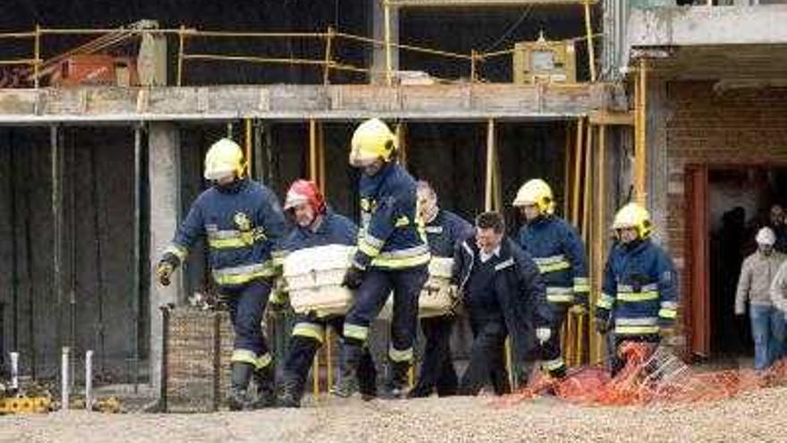 Varios bomberos trasladan el cadáver de Fidel Cifuentes, el hombre de 84 años que desapareció de su domicilio de Cuenca el pasado miércoles cuando iba a canjear lotería premiada, tras ser encontrado hoy sin vida en el complejo en construcción Ars Natura, donde cayó desde un cuarto piso de un edificio en obras.