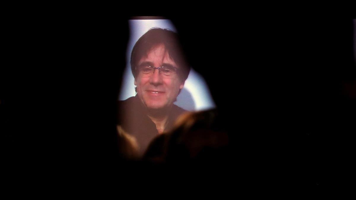 Carles Puigdemont conversa por videoconferencia con candidatos y simpatizantes durante la inauguración de la sede de campaña de Junts per Catalunya.