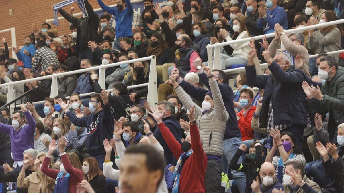 En la imagen superior, los aficionados del Oviedo Baloncesto celebran una canasta en el partido de ayer. Abajo, Vícitor Menéndez, con su camiseta del OCB y su bufanda del Estudiantes. | Miki López / M.R.