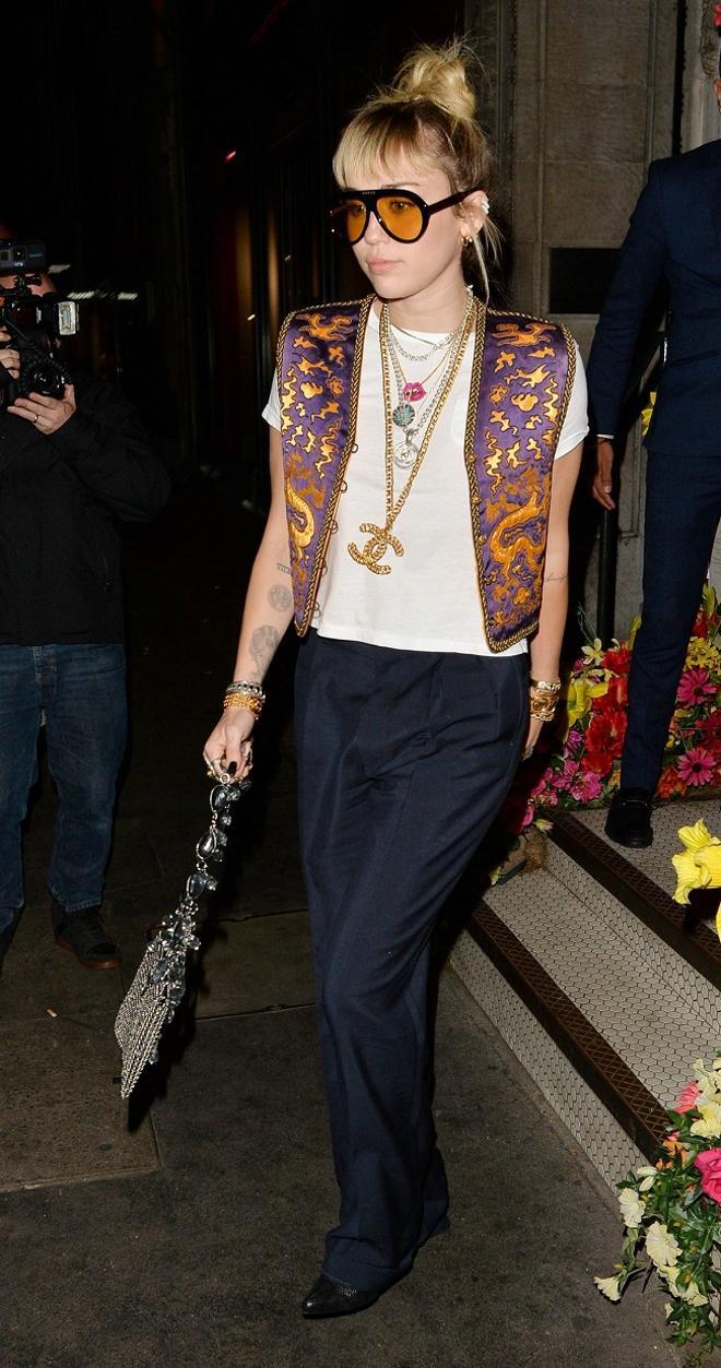 Miley Cyrus sale de un restaurante en Londres, con el look con moño + flequillo