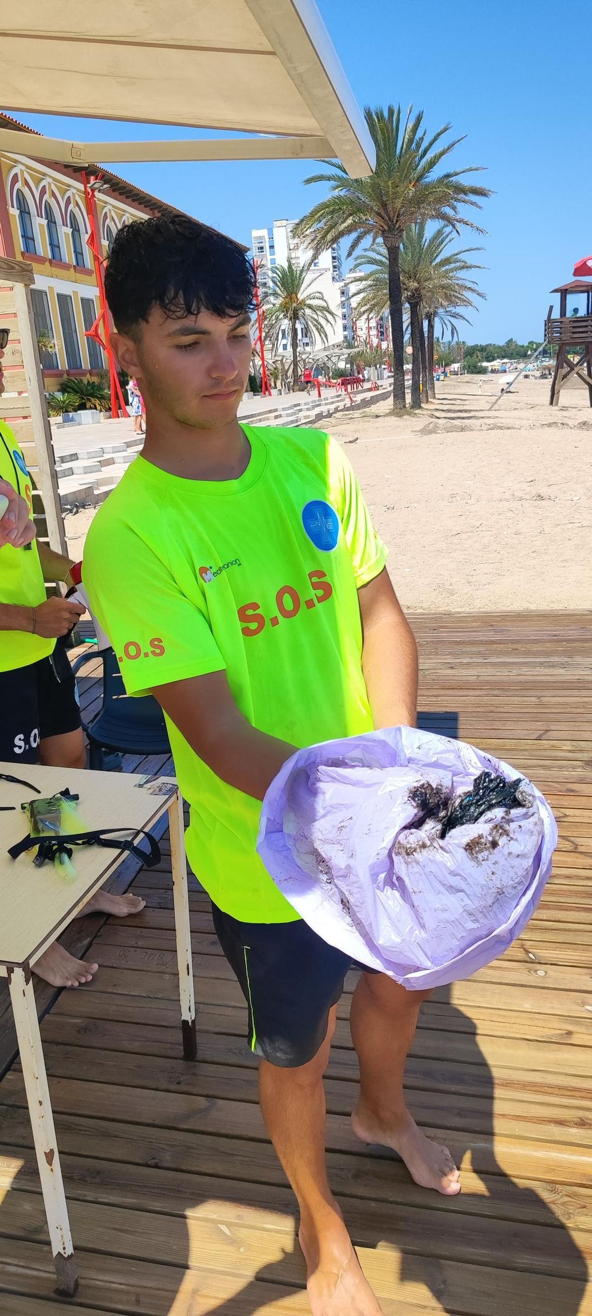 Un miembro del servicio de salvamento, con una muestra de chapapote.