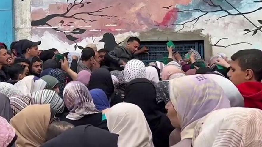 Cientos de palestinos se apiñan a las puertas de un almacén para conseguir algo de comida.