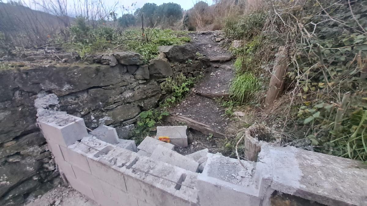 Un murete derribado junto al acceso a las vías.